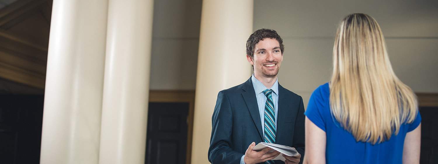 One graduates smiles at another: Explore the online MA in Law - Healthcare Law program offered by Regent University.
