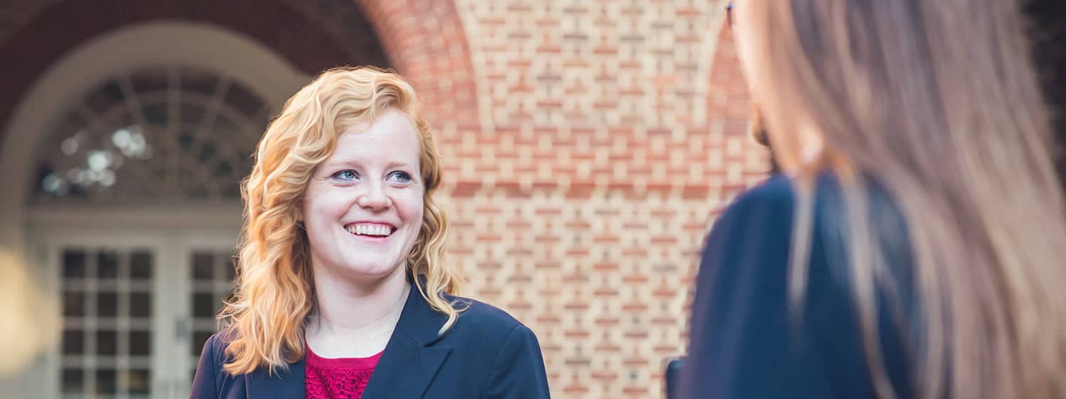 One graduate smiles at another: Pursue the MA in Law – Nonprofit Organization Law degree at Regent University.