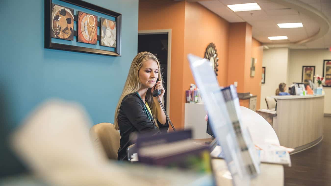 A healthcare worker answers a phone call: Explore the MBA in Healthcare Management at Regent University.