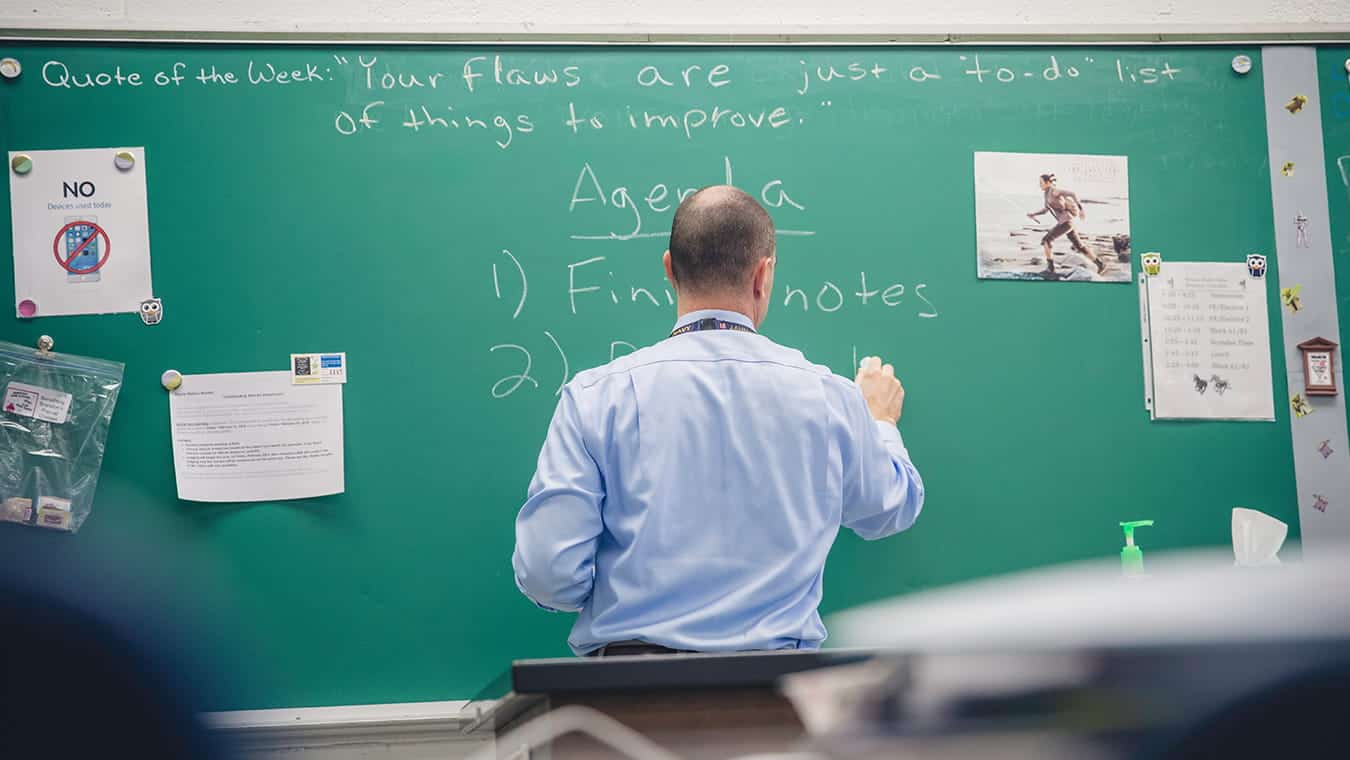 A teacher writes on a chalkboard: Pursue an Ed.S. in Leadership in Mathematics Education at Regent University.
