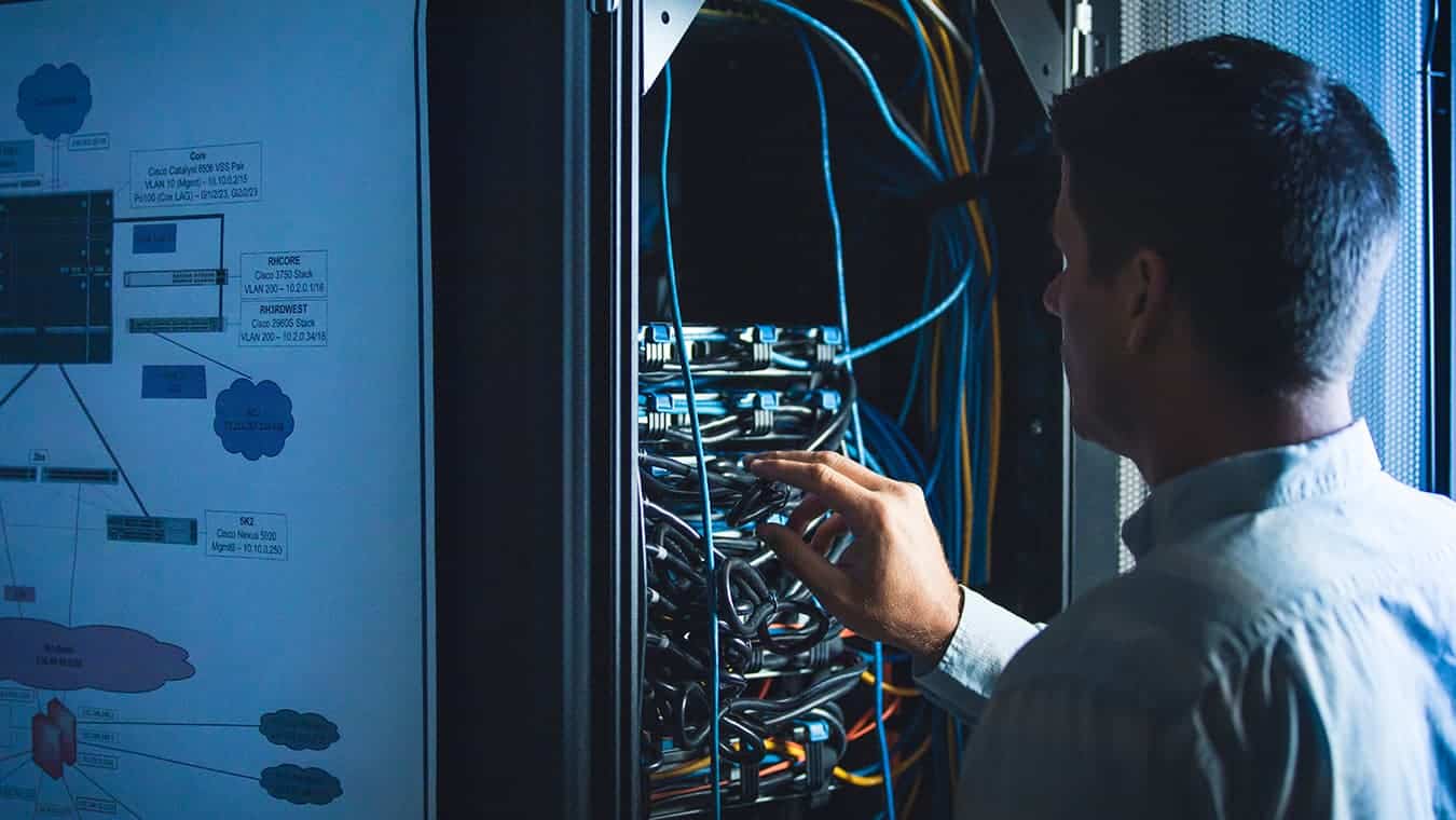 A person works in the server room: Explore Regent's MA in National Security Studies - Cybersecurity Policy program (online / Virginia).