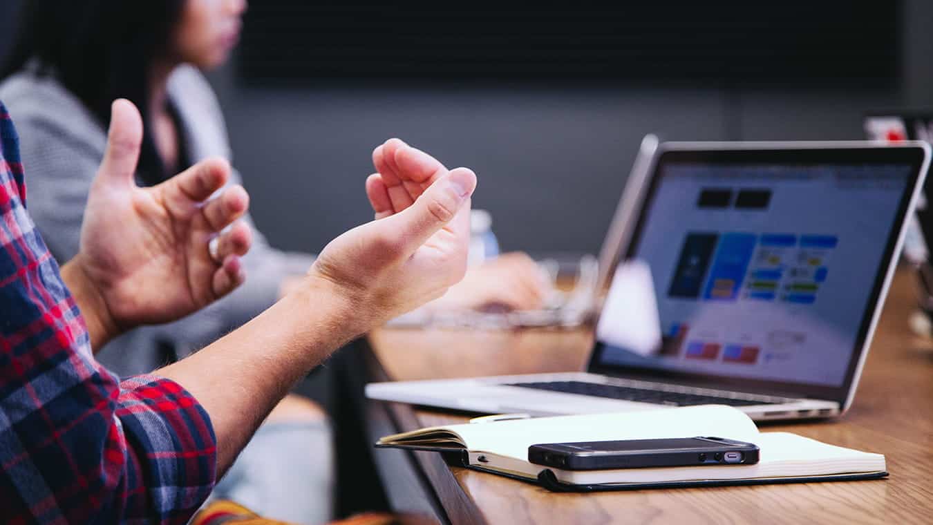 Hands during a meeting: Explore Regent's MAOL degree program with a concentration in Small Business Technology Management.