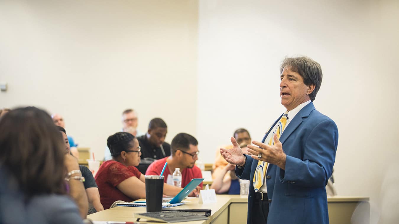 A professor teaching a class: Be equipped to excel through Regent's Ph.D. Higher Education Leadership and Management.