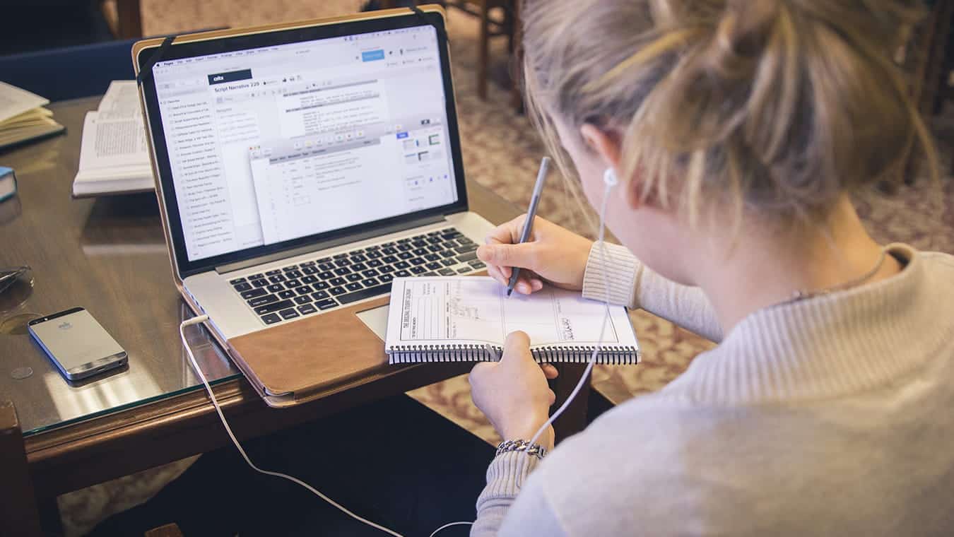 A student taking notes in front of her laptop: Explore Regent University’s communication minor, offered online and in Virginia Beach, VA 23464.