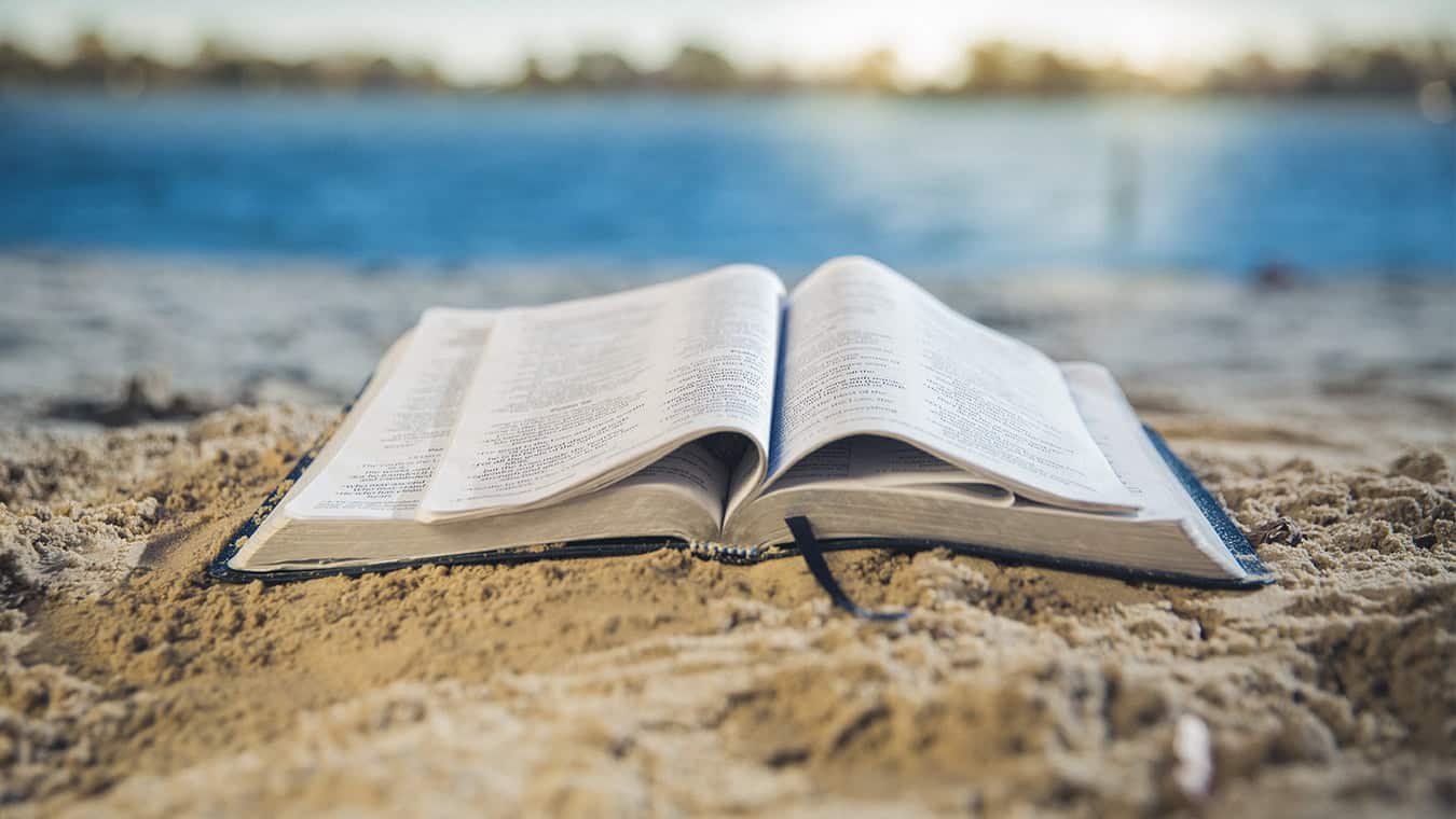 An open book on a beach: Regent University offers a Biblical studies minor online and in Virginia Beach, VA 23464.