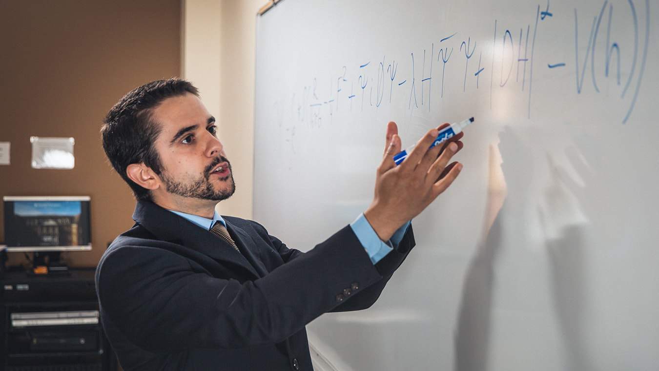A professor working on a whiteboard: Regent University offers a mathematics minor on campus in Virginia Beach, VA 23464.