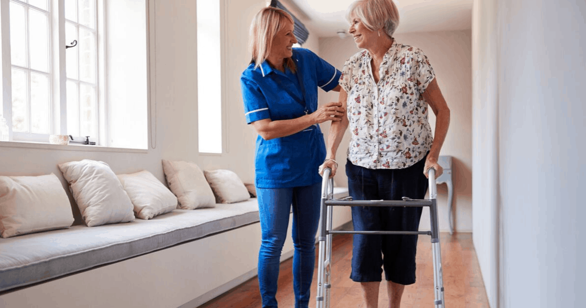 an nurse helping a woman walk with a walker.
