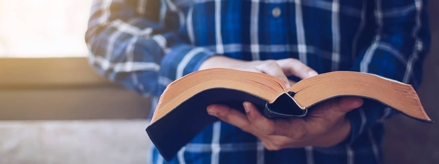 An open book in the hands of a person: Explore the Minor in Christianity and Culture offered by Regent University, Virginia Beach.