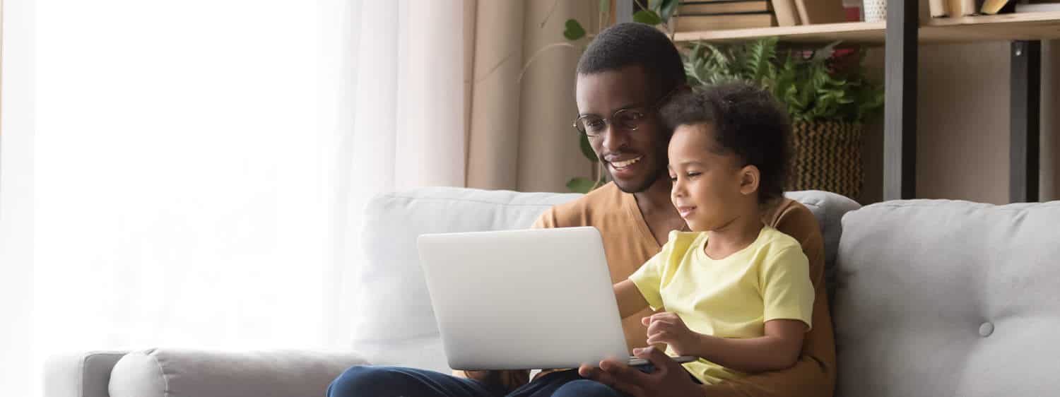 A person and his son look at a laptop screen.