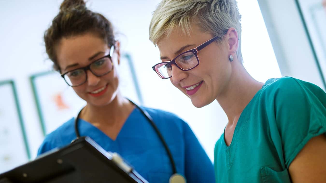 Two healthcare professionals look at a chart: Pursue the Master of Arts in Organizational Leadership in Healthcare Management at Regent University.