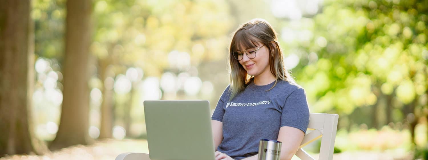 A girl looks at her laptop at Regent University's beautiful campus in Virginia Beach, VA 23464.
