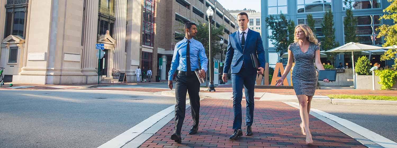 A group in professional attire crosses a road in Norfolk, Virginia.