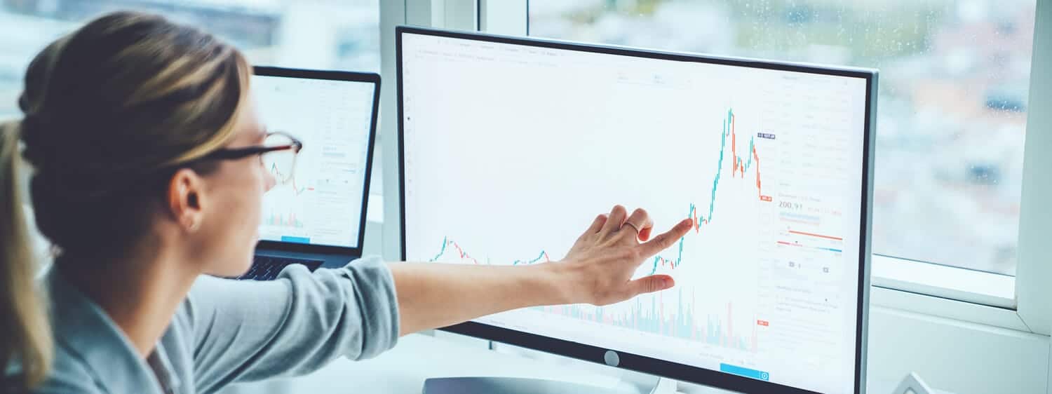 A lady pointing at a graph: Explore the MBA in Business Analytics program at Regent University.