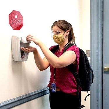 A member of the Regent University community uses a hand sanitizer.