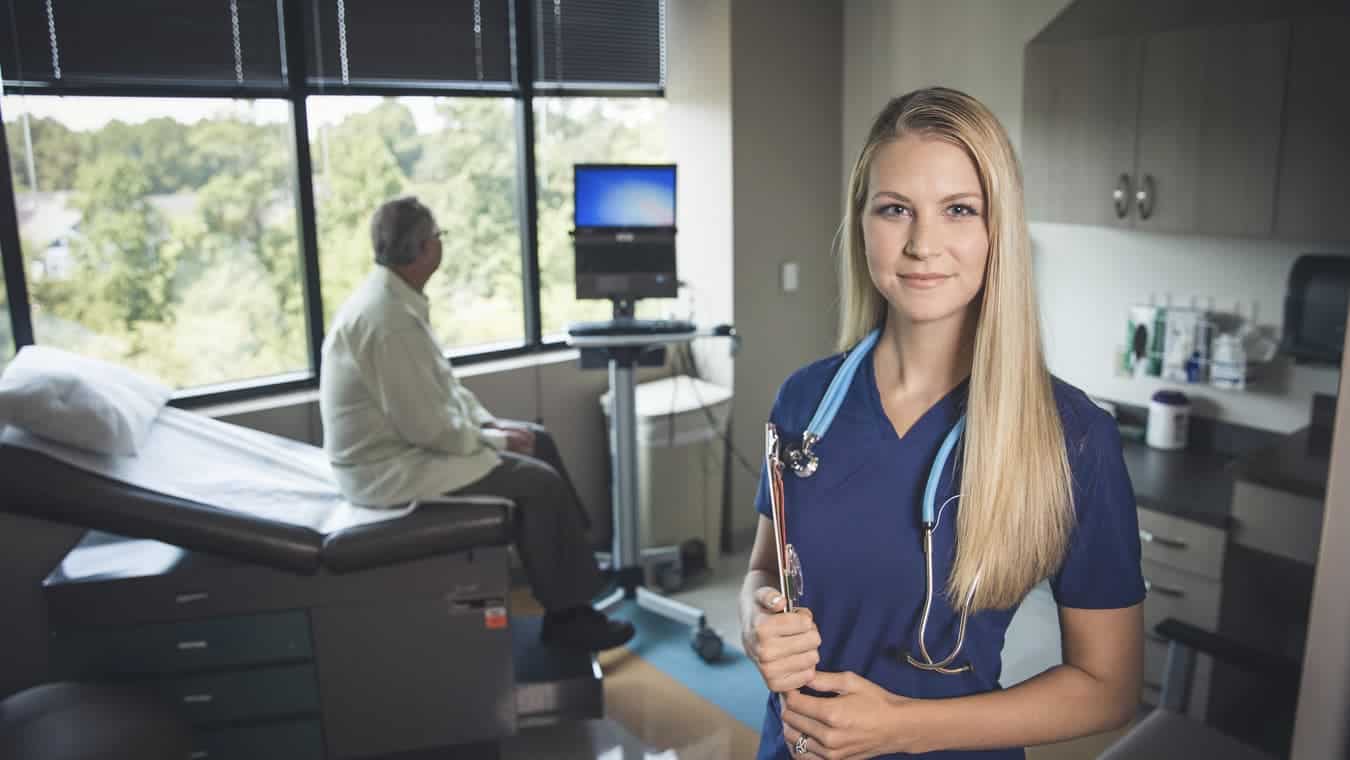 A nurse with a stethoscope and clipboard. Earn your healthcare management degree or nursing degree online at Regent University.