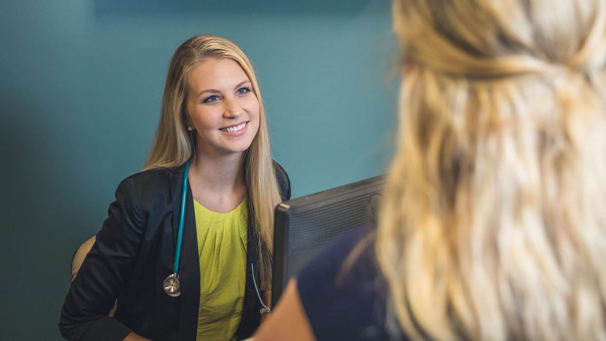 A nurse smiles as she meets with a patient. Earn your medical and health services management position with a degree from Regent University.