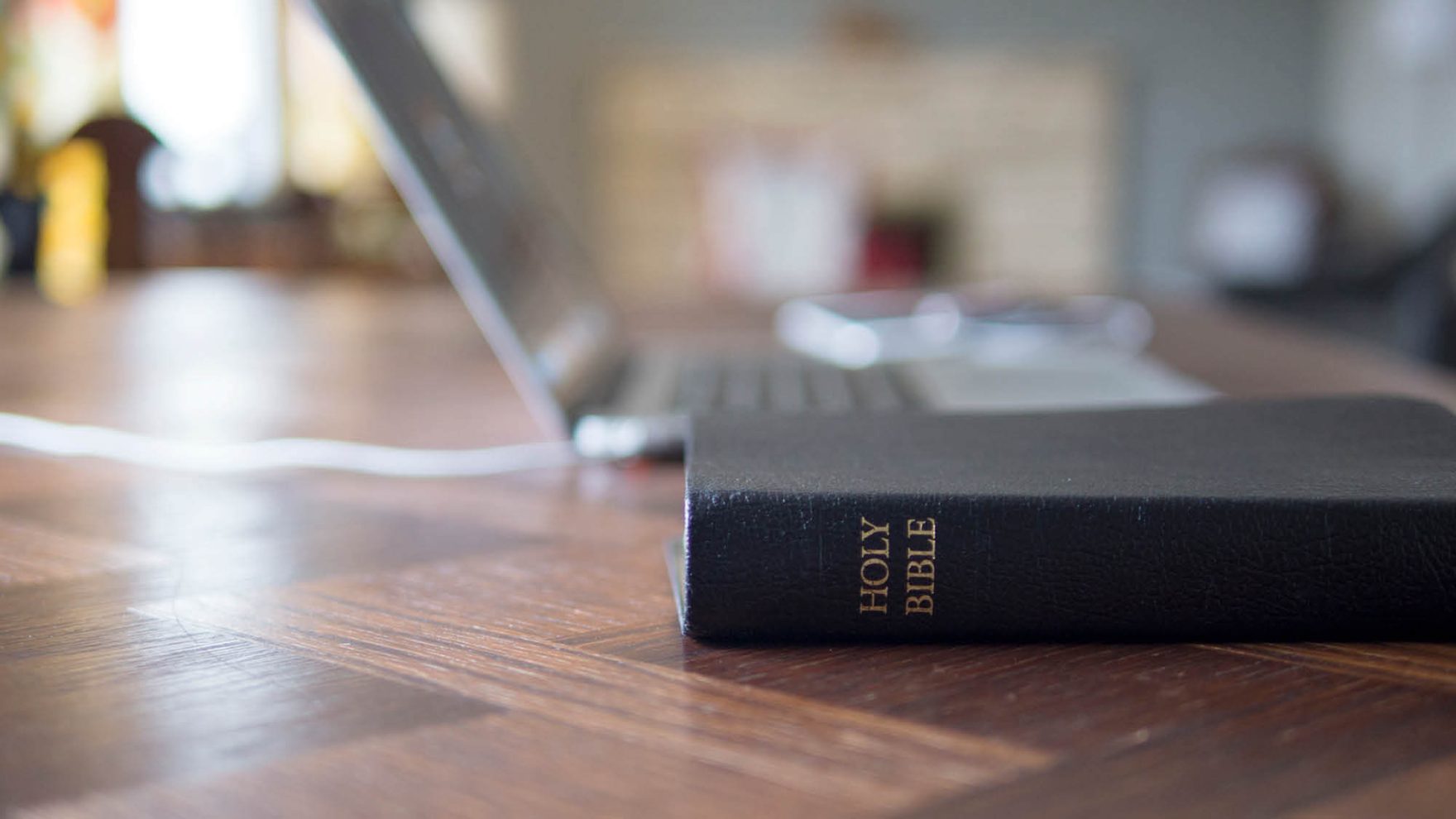The Holy Bible next to a laptop: Explore the master of Divinity Biblical Studies at Regent University.