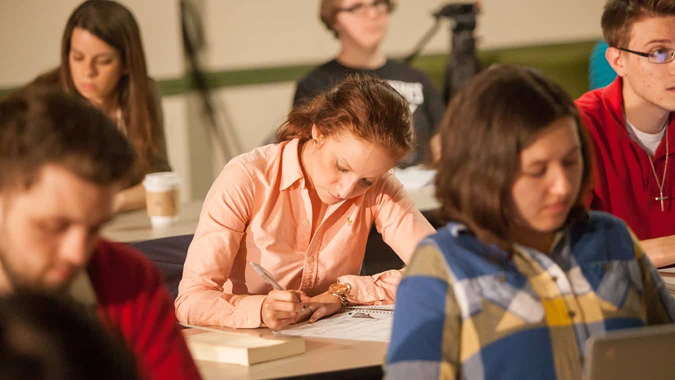 Students writing during class: Pursue an Associate in Business degree at Regent University.