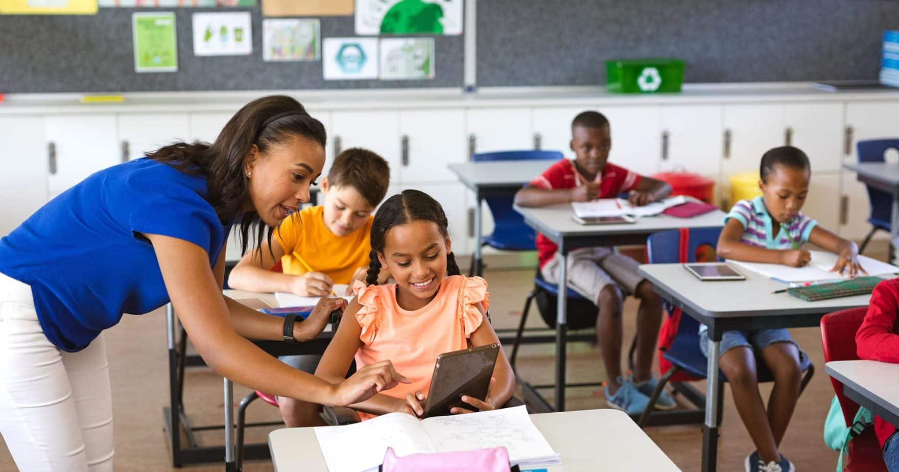 How to become a special education teacher: a female teacher shows a female special needs student how to use a tablet.