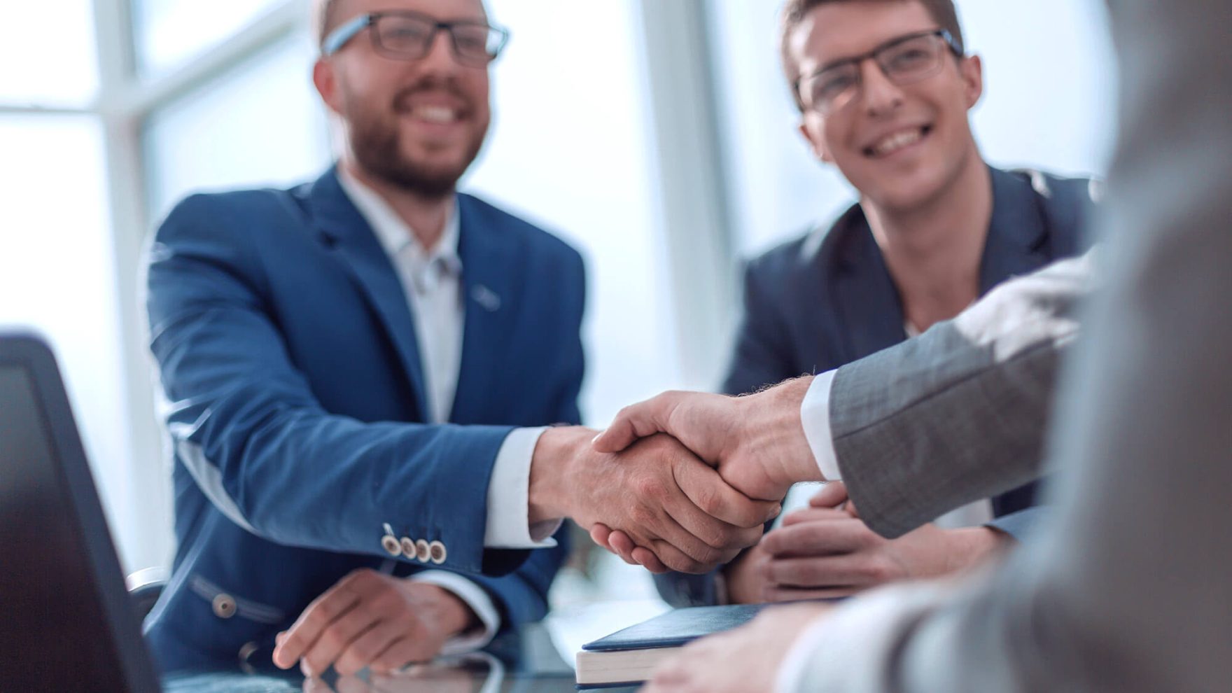 People shaking hands in a business setting: Discover more about Regent's online DBA in Corporate Consulting.