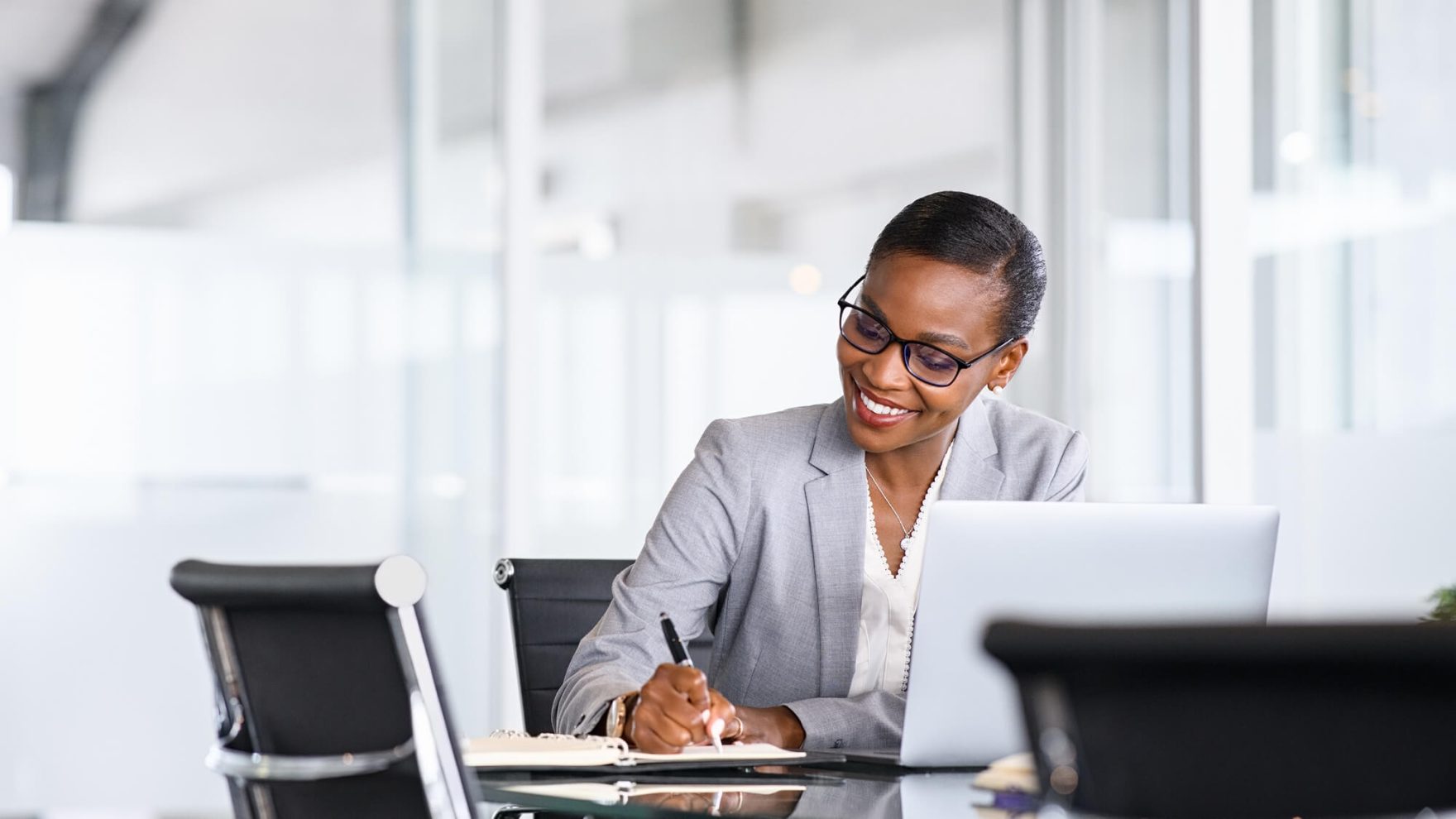 Business woman taking notes: Explore the Ph.D in Business Administration online.