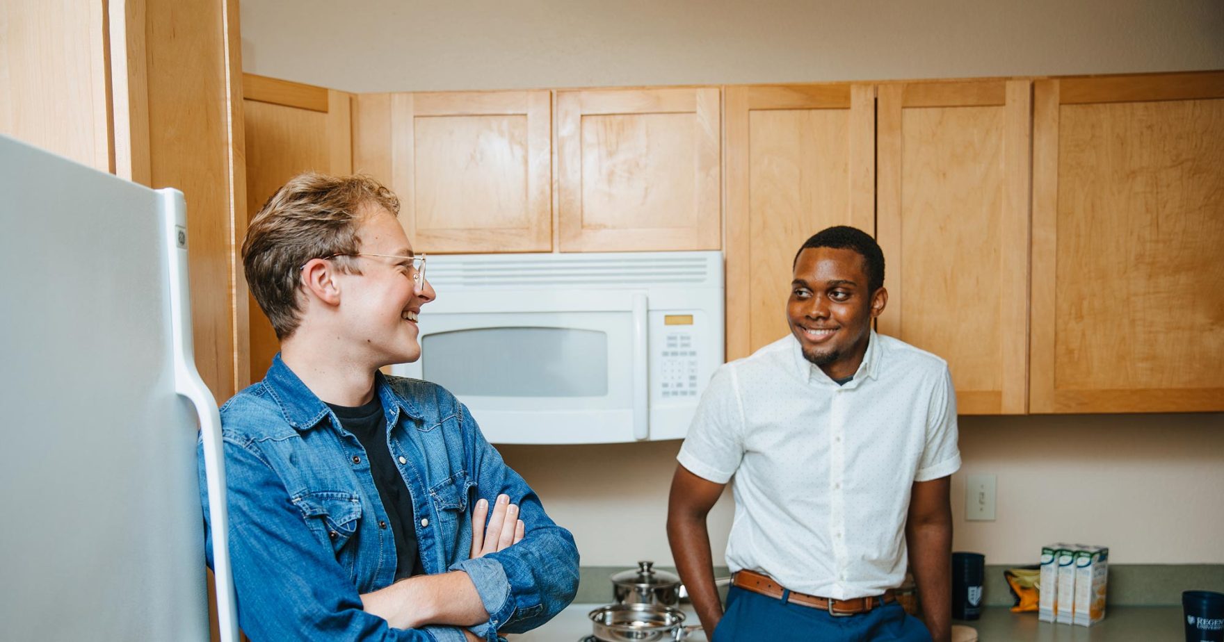 Photo of two student smiling and talking in their dorm apartment.