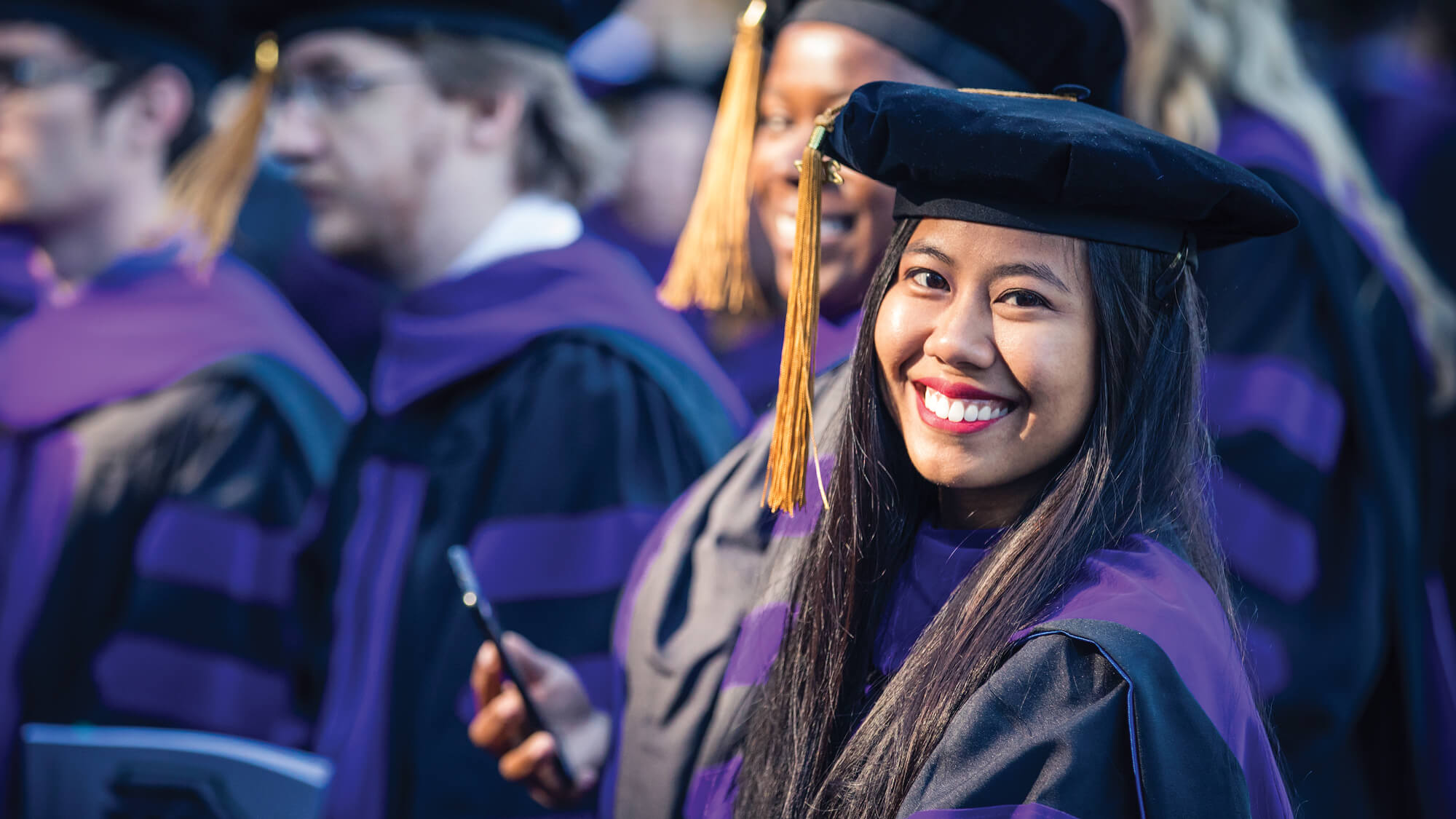 A photo of student in graduation regalia: Learn more about Regent's student testimonials.