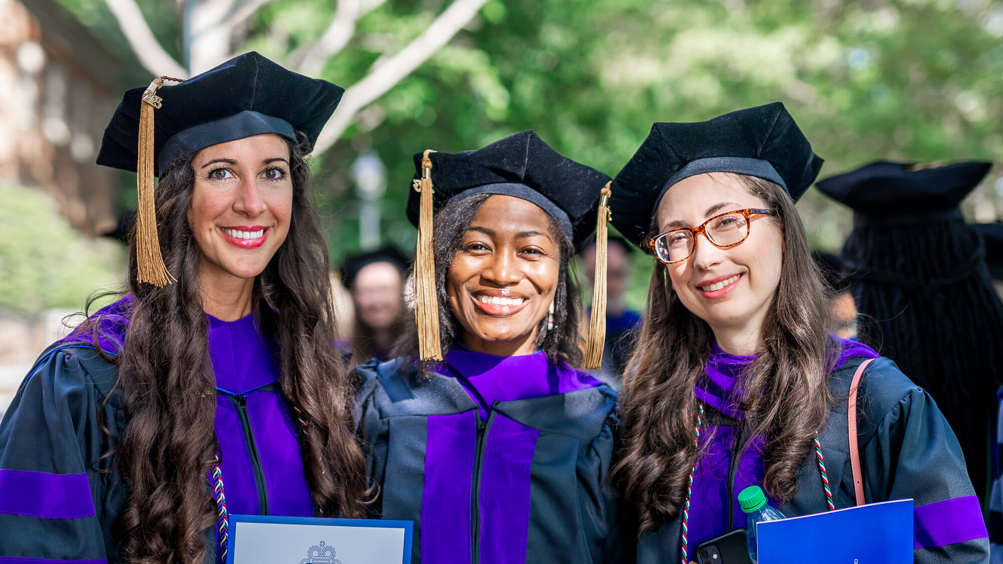 Three smiling Regent Law graduate students on Commencement Day in Virginia Beach, Virginia.