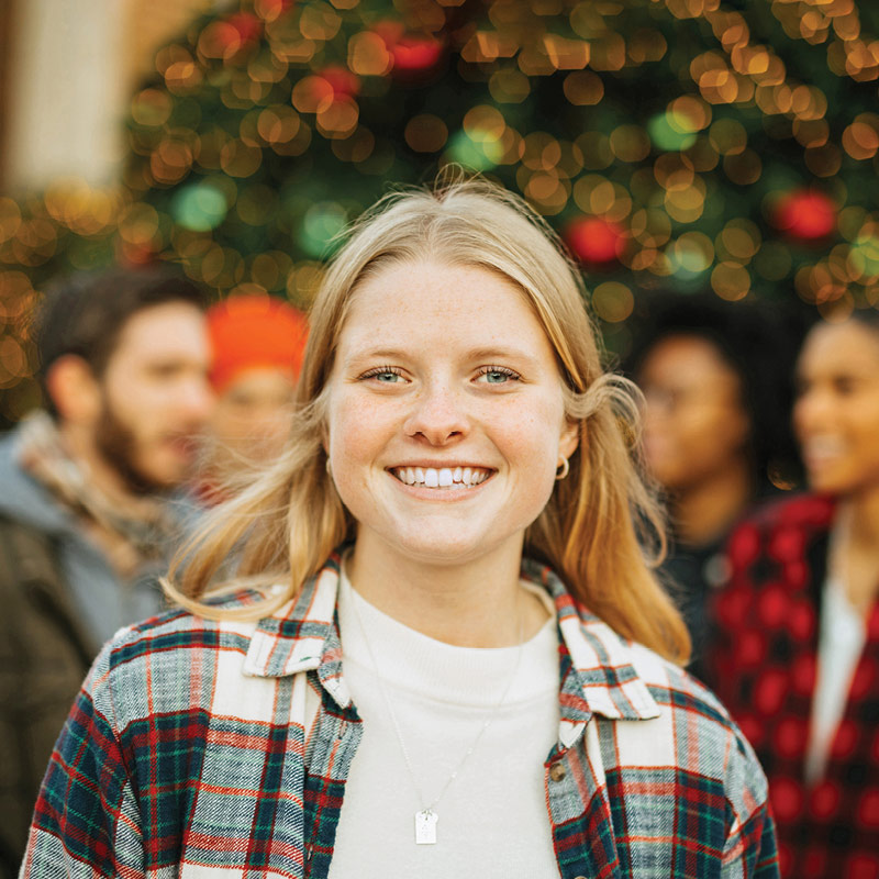 Regent University student in front of a Christmas tree: among top colleges and universities in VA.