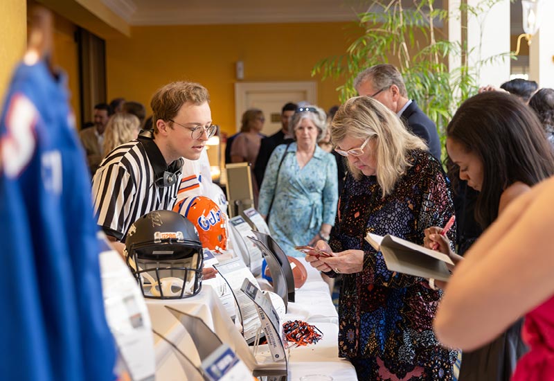 Tim Tebow Speaks at Regent University Night of Giving attendees view auction items