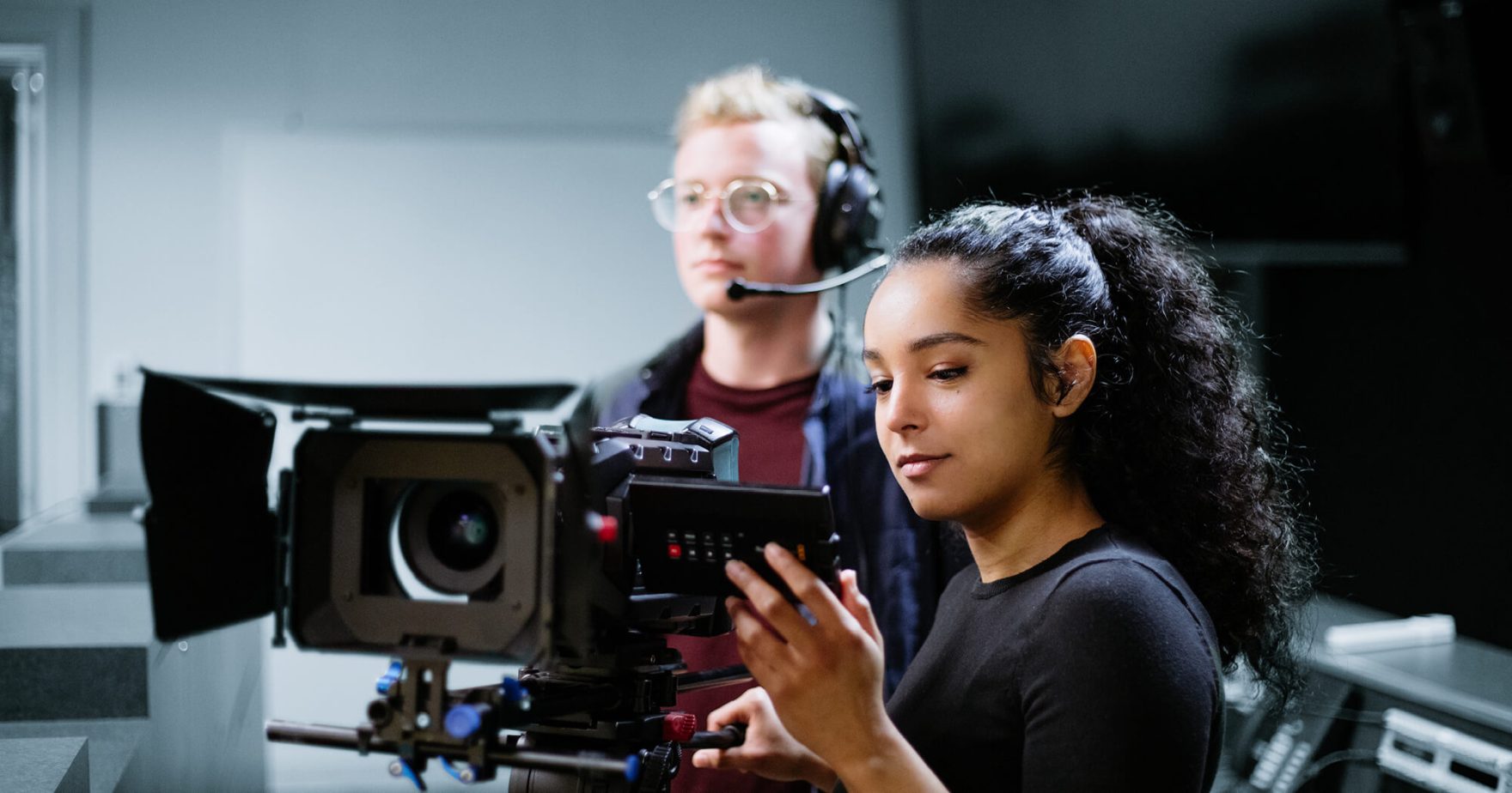 Regent Students holding a film camera working on a film set.