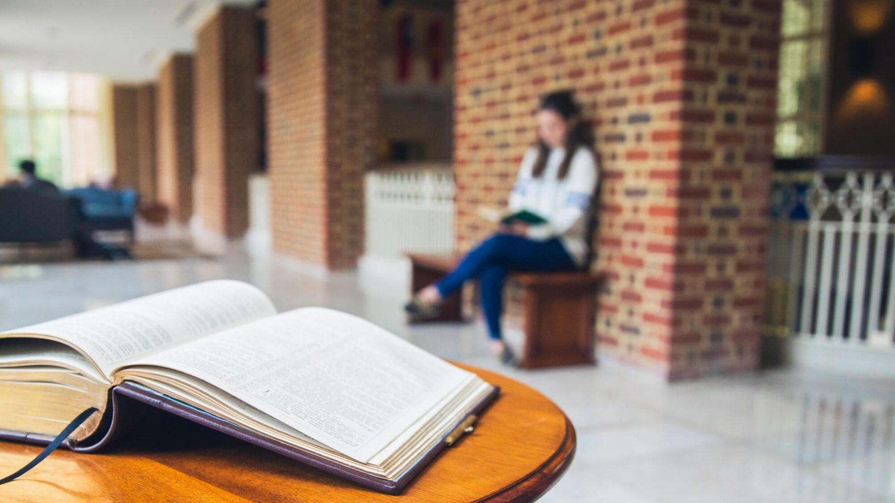 a book on the table with a Regent student in the background.