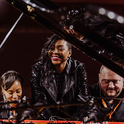 Jade Simmons performing on stage with fellow musicians, smiling behind a piano