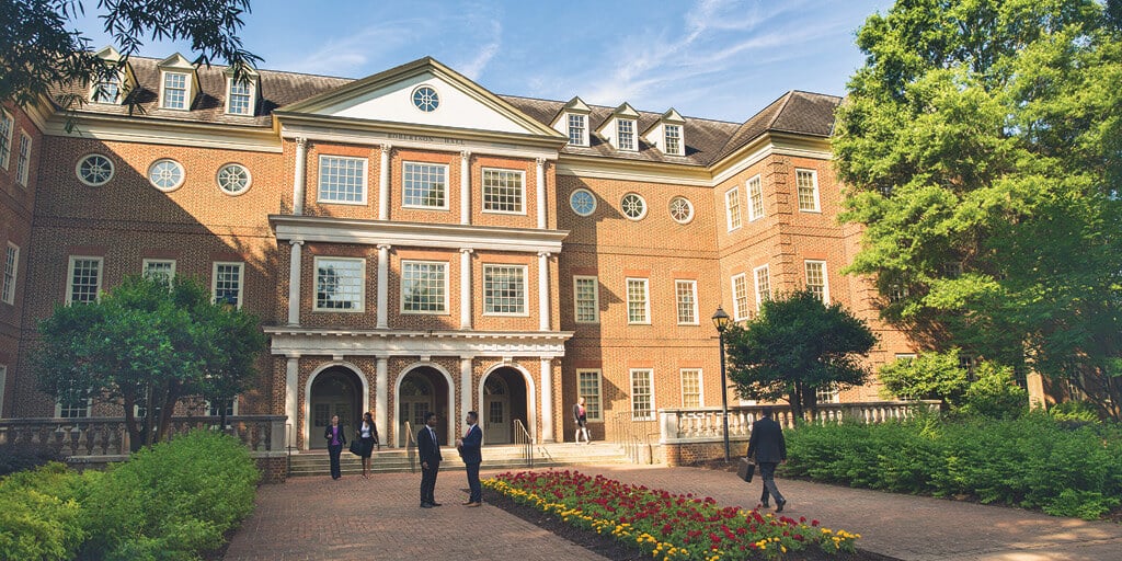 Front view of Robertson Hall at Regent University, home of Regent Law, with alumni and visitors walking near the entrance.