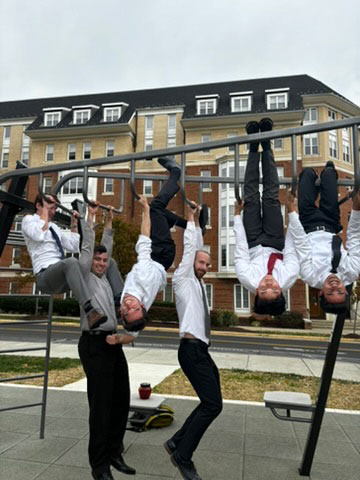 Two team members seated at a table in front of a chalkboard during competition preparation