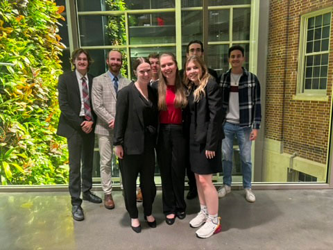 Moot Court team holding a teammate horizontally in front of a law school building
