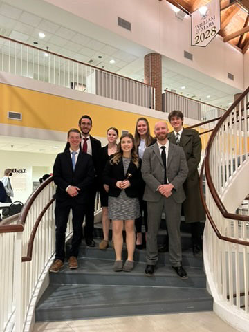 Group photo of nine team members standing together with awards