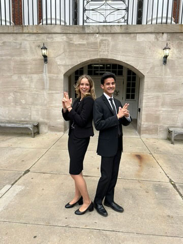 Two team members posing back-to-back outside in mock spy style