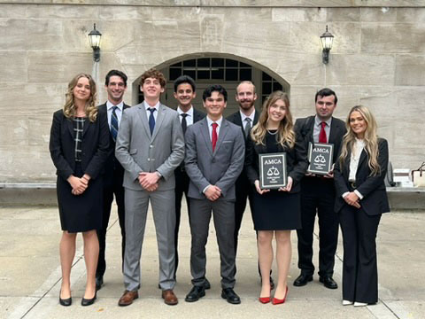 Group of students posed on an indoor staircase for a formal team photo