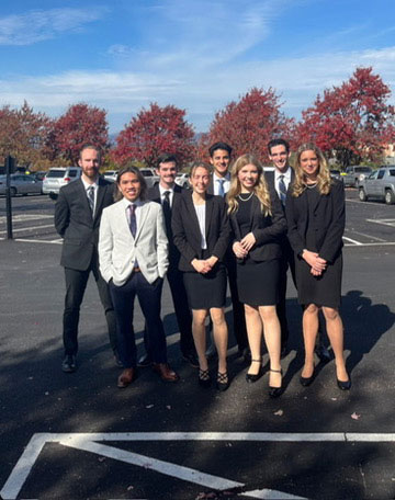 Team members posing back-to-back with gavels at a law school backdrop