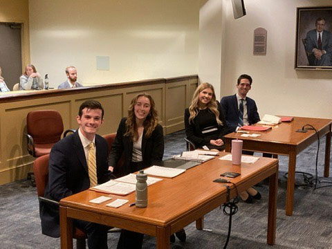 Teammates holding individual awards on the steps of a law school building