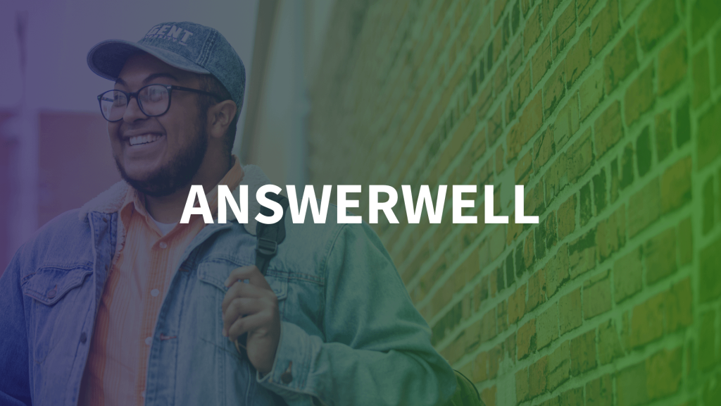 AnswerWell - A smiling young man wearing glasses, a denim jacket, and a cap walks past a brick wall with a gradient overlay transitioning from blue to green