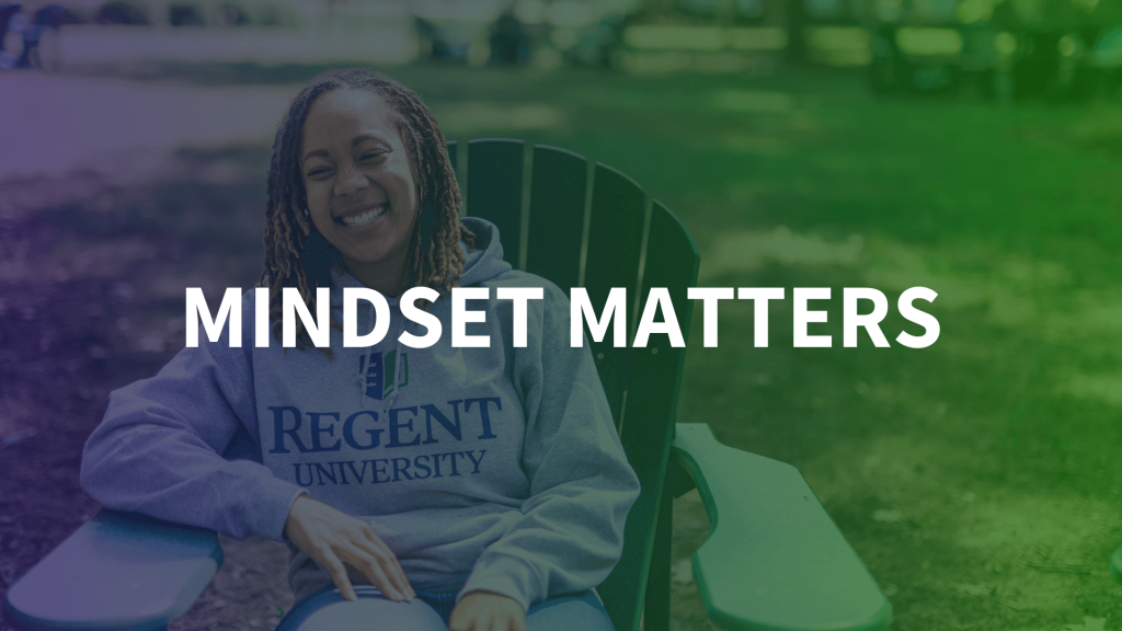 Mindset Matters - A young woman wearing a Regent University hoodie sits relaxed in a green Adirondack chair outdoors, smiling with a gradient overlay transitioning from blue to green