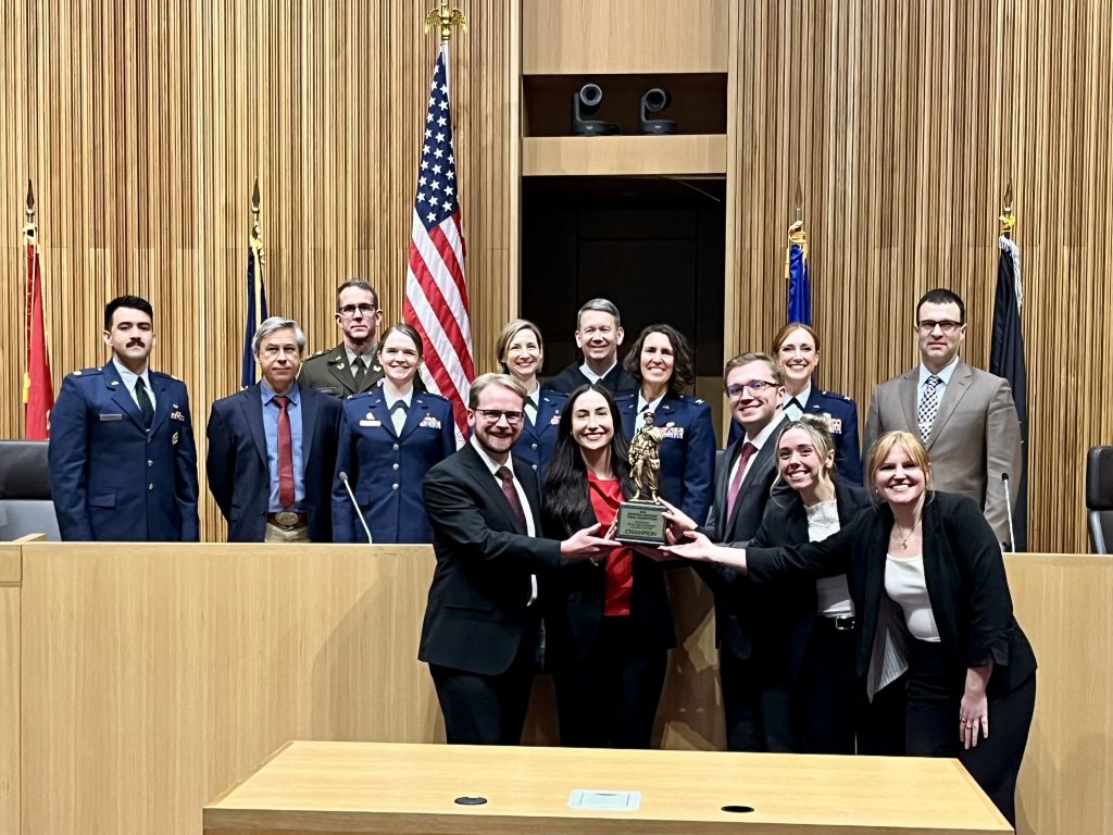 Regent Law Trial Advocacy Team members and coaches pose with the championship trophy after winning the National Military Trial Competition in Syracuse, New York.