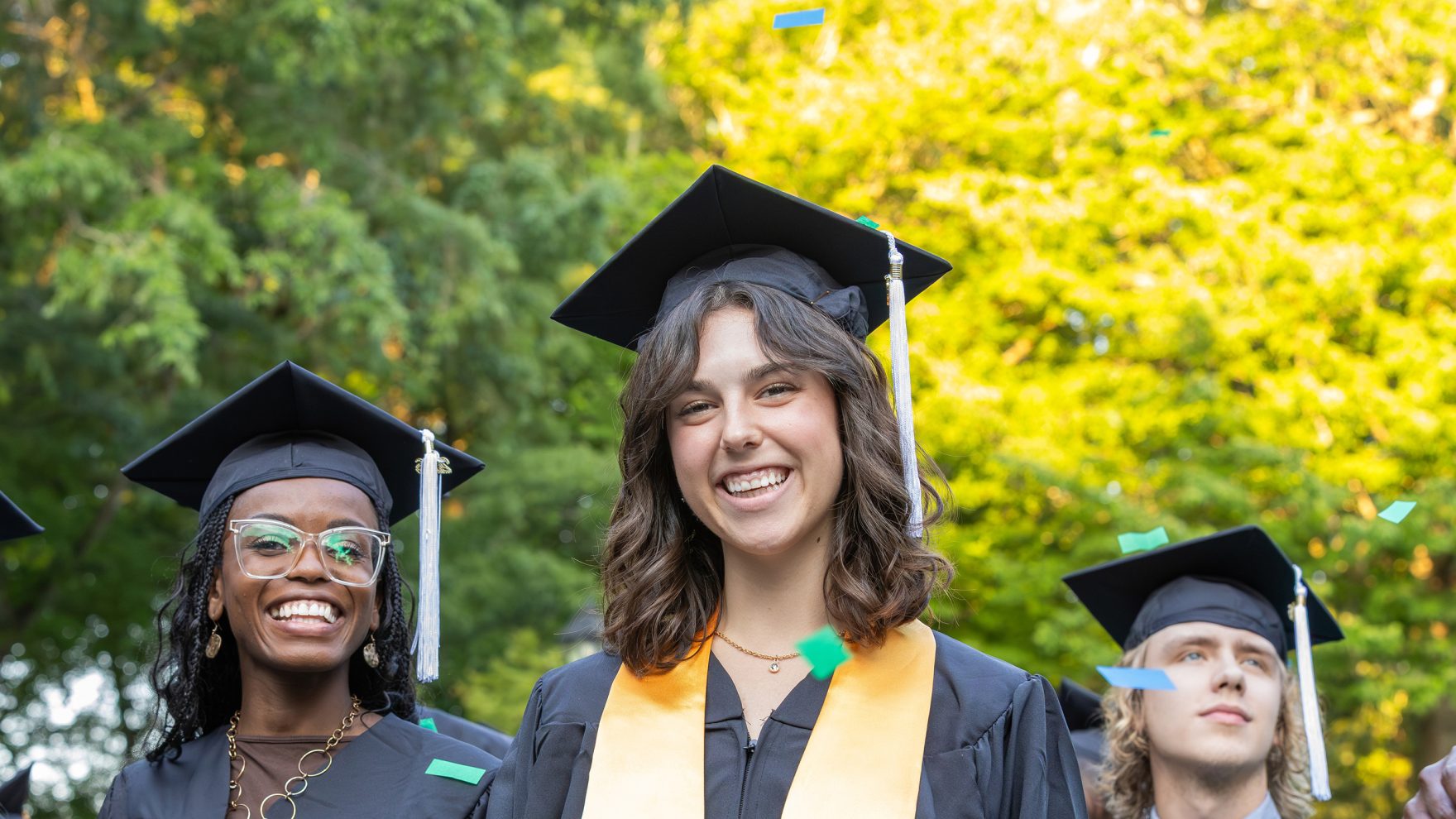 Three Regent University students in regalia, getting ready to graduate on campus in Virginia Beach, Virginia.