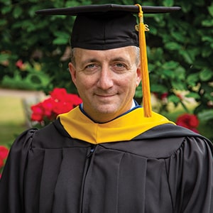 Rob Hess, military chaplain and Master’s graduate, poses in his cap and gown at Regent University.