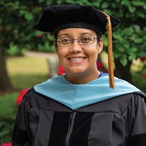 Allisha Beerwart, Doctor of Education in Special Education graduate, smiles in academic regalia on Regent University’s campus.