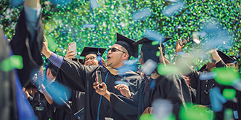 Regent University graduates celebrating with confetti at commencement 2018