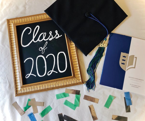 Class of 2020 graduation cap, tassel, diploma and chalkboard sign with confetti