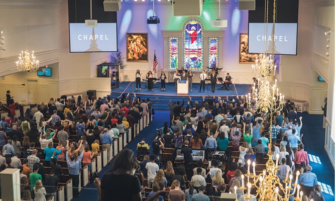 Students and attendees worshiping in Shaw Chapel with worship team on stage